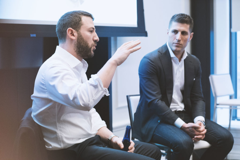 A panel of two men in suits in discussion 